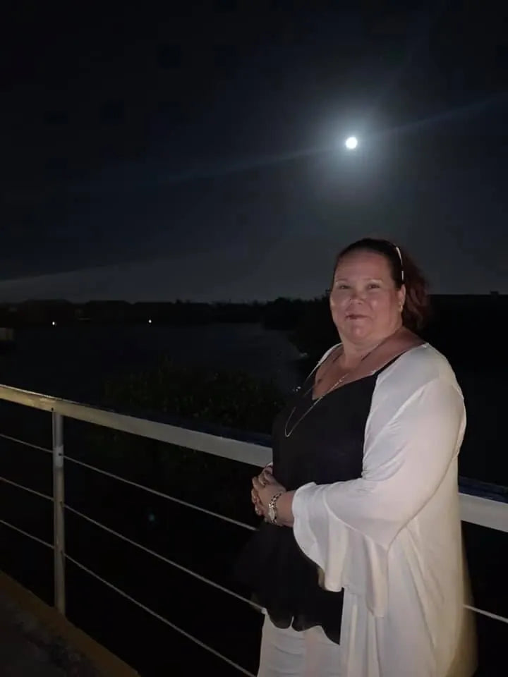Monique Collins standing by the water under a full moon